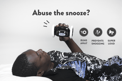Black NeXtime Clocks Clocky alarm clock on wheels with digital display on a modern bedside table.