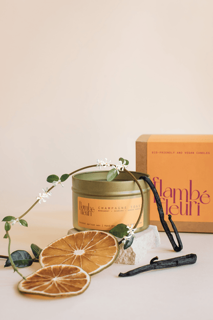 Flambé Fleuri Champagne Toast Candle in a decorative tin, featuring a champagne glass and toast design for celebratory ambiance.
